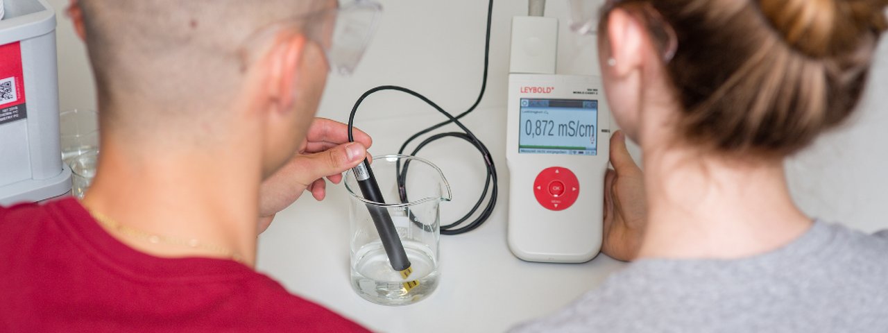 Ein Schüler und eine Schülerin untersuchen im Chemieunterricht den pH-Wert einer Säure. Dazu verwenden sie das Mobile-CASSY 2 WLAN zur Messwerterfassung, LD DIDACTIC GmbH