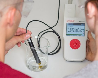 Ein Schüler und eine Schülerin untersuchen im Chemieunterricht den pH-Wert einer Säure. Dazu verwenden sie das Mobile-CASSY 2 WLAN zur Messwerterfassung, LD DIDACTIC GmbH